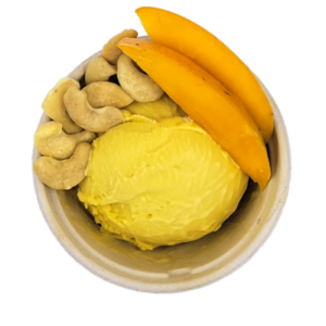 Scoop of mango ice cream in a bowl with cashews and mango slices.